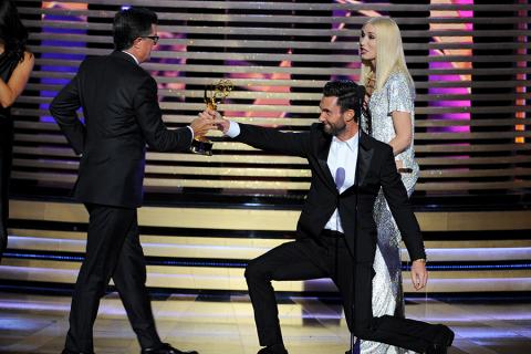 Adam Levine (second from right) of The Voice and Gwen Stefani (r) of The Voice present Stephen Colbert (l) of The Colbert Report an award at the 66th Emmys.  